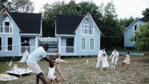 A diverse family plays tug of war outdoors near modern houses, enjoying a sunny day.