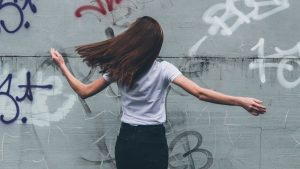 woman in white t-shirt and black pants standing in front of white wall with red