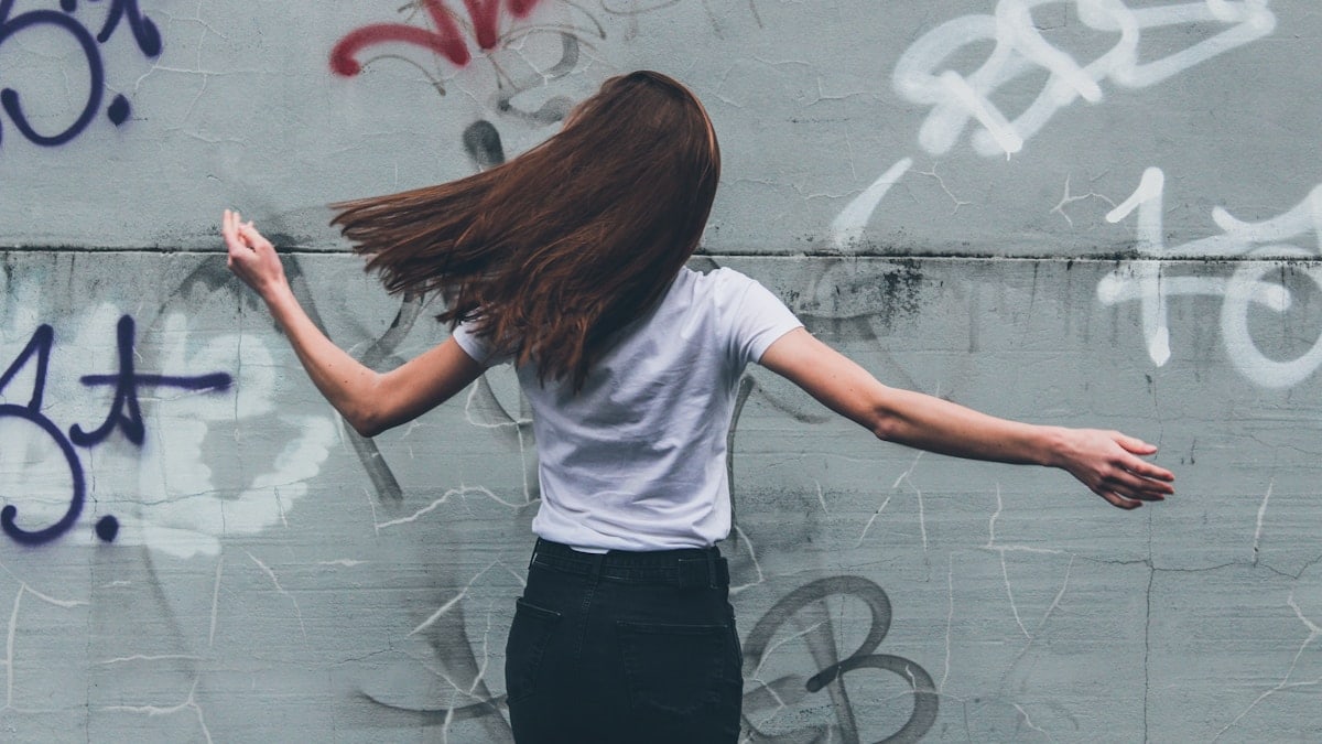 woman in white t-shirt and black pants standing in front of white wall with red